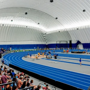 Blue indoor running track inside the Air Dome, with athletes and spectators